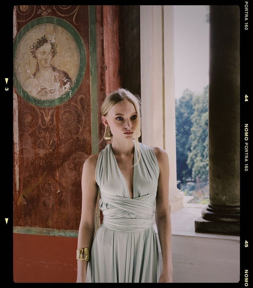 Nikita Lauffer in a long sage-green dress before a fresco