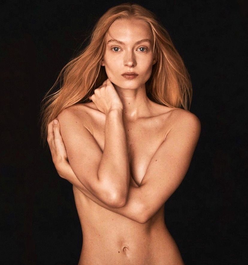 Portrait of Nikita Lauffer with long hair and her arms crossed over her chest, dark background